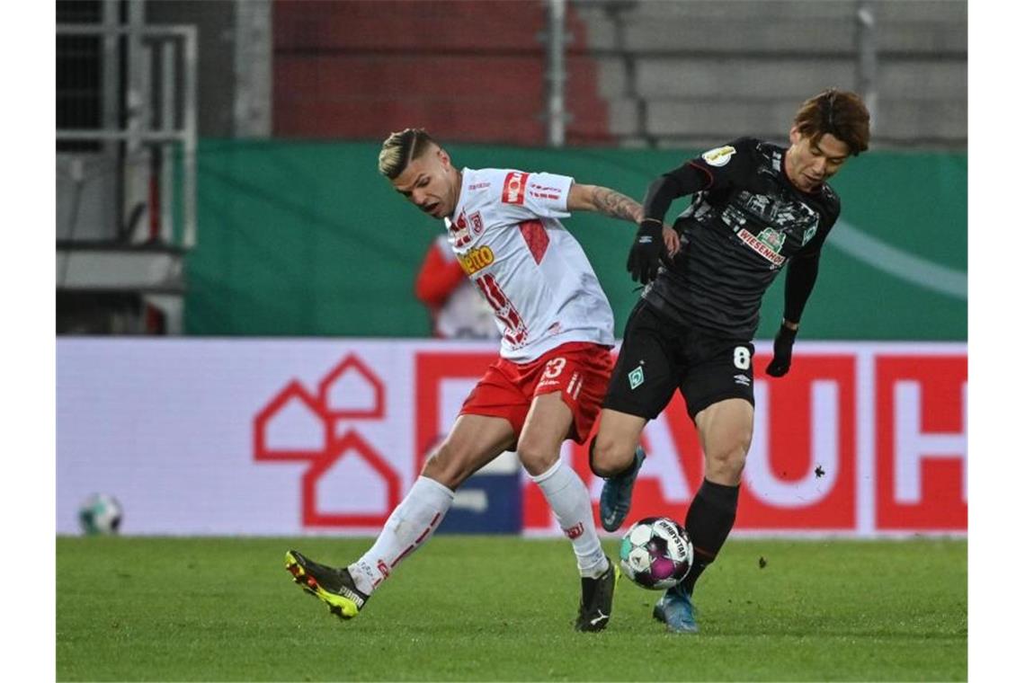 Regensburgs Jan Elvedi und Bremens Yuya Osako (r) kämpfen um den Ball. Foto: Armin Weigel/dpa