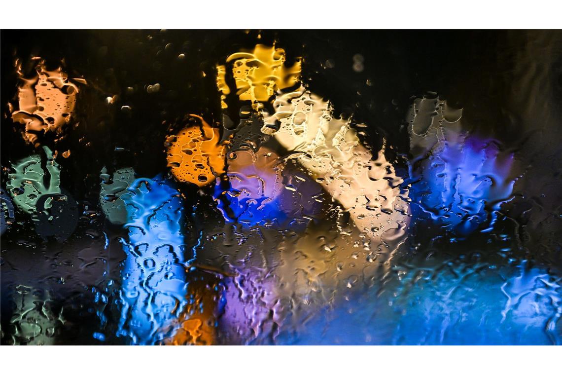 Bilder des Tages Regentropfen, die im Süden von Baden-Württemberg auf eine Windschutzscheibe prasseln, werden vom Licht der Straßenlampen angestrahlt.