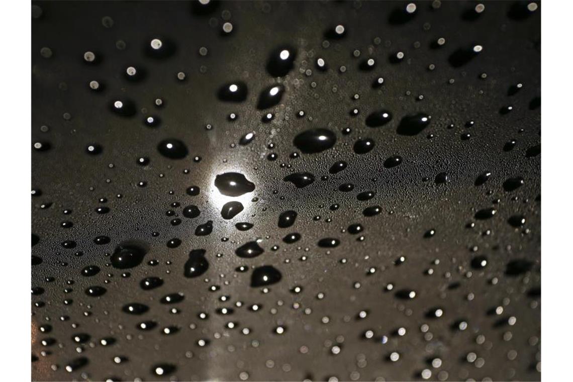 Regentropfen liegen im Licht einer Straßenlaterne auf der Windschutzscheibe eines Autos. Hoch „Manfreed“ zieht weiter, es wird kühler und nass. Foto: Karl-Josef Hildenbrand/dpa