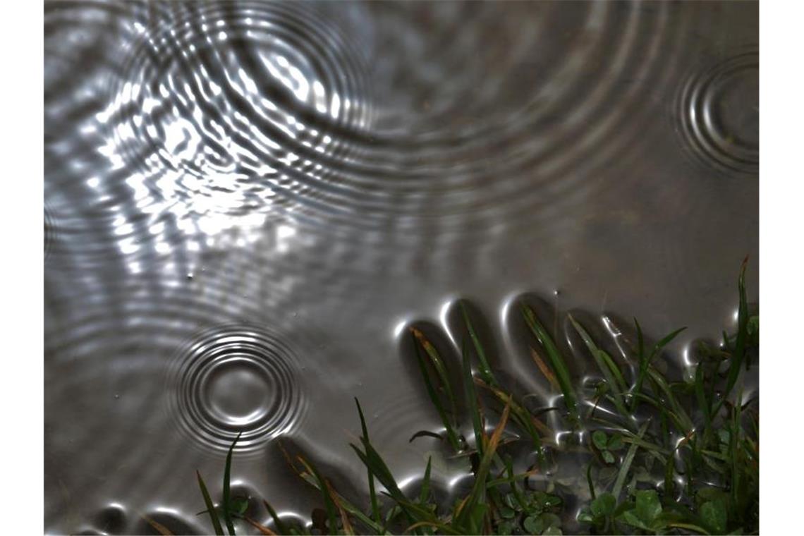 Wetter wird unangenehmer: Starkregen und Hagel möglich Regentropfen prasseln auf eine Pfütze, in der sich die Sonne spiegelt. Foto: Karl-Josef Hildenbrand/Archivbild