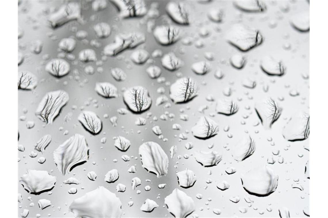 Regentropfen sind auf einer Autoscheibe zu sehen. Foto: Mohssen Assanimoghaddam/dpa/Symbolbild