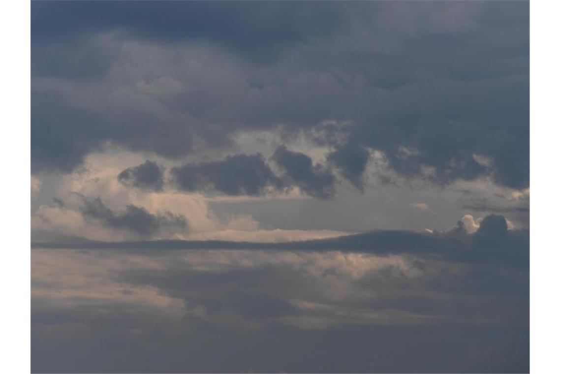 Regenwolken verdecken die Sonne am Himmel. Foto: Angelika Warmuth/dpa/Symbolbild