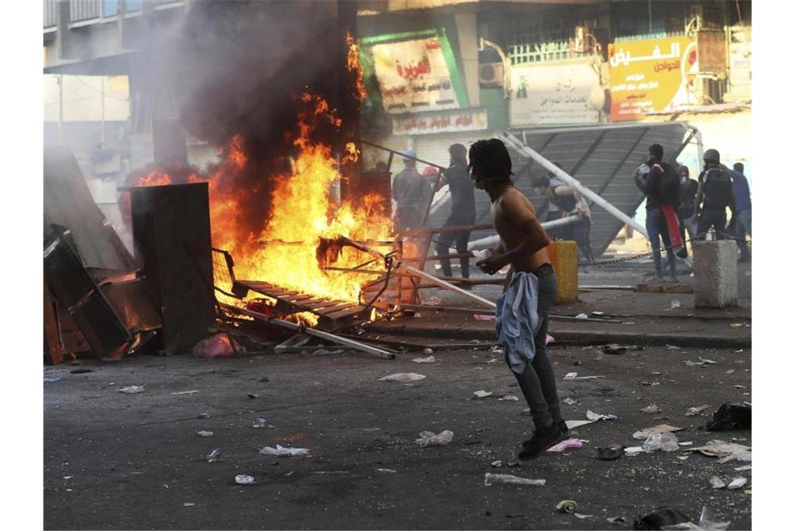 Regierungsfeindliche Demonstranten haben in Bagdad Barrikaden in Brand gesteckt und Straßen blockiert. Foto: Hadi Mizban/AP/dpa