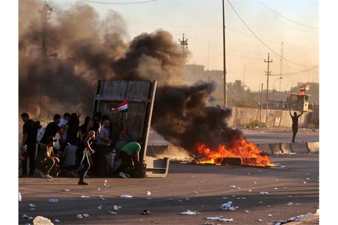 Fast 100 Tote bei Protesten im Irak Regierungsfeindliche Demonstranten haben während einer Demonstration in Bagdad Feuer gelegt und eine Straße blockiert. Foto: Khalid Mohammed/AP/dpa