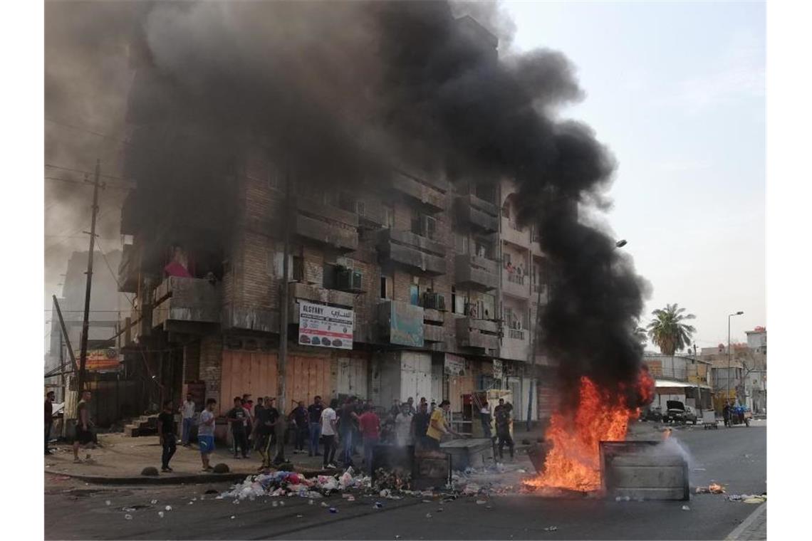 Regierungsgegner haben vor einem Gebäude Straßenblockaden errichtet und ein Feuer entfacht. Foto: Hadi Mizban/AP/dpa