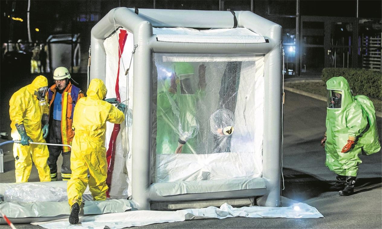 Reine Vorsichtsmaßnahme: Zwei Feuerwehrleute in grünen Chemieschutzanzügen werden nach ihrem Einsatz im Duschzelt der Backnanger Feuerwehr gereinigt. Foto: 7aktuell/S. Adomat