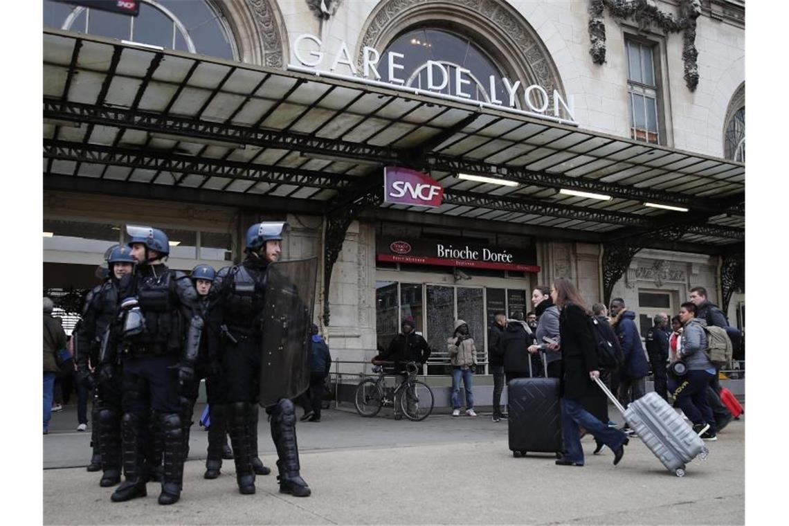 Keine Streikpause zu Weihnachten in Frankreich Reisende am Gare de Lyon, der während einer Demonstration der streikenden Eisenbahner von Polizisten bewacht wird. Foto: Francois Mori/AP/dpa