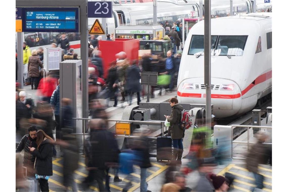 Reisende gehen am Münchner Hauptbahnhof über eine Plattform. Foto: Tobias Hase/dpa