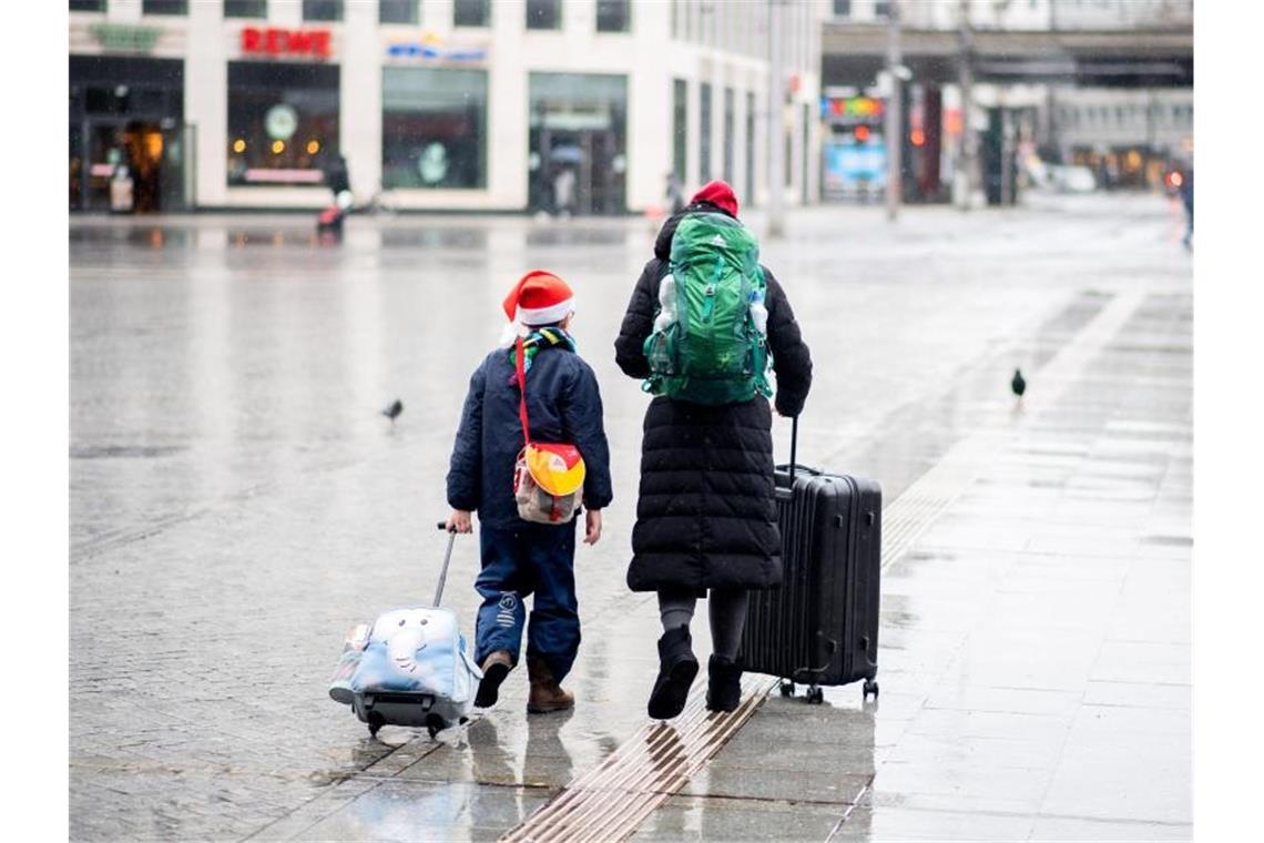 Reisende gehen an Heiligabend mit ihrem Gepäck über den Vorplatz am Hauptbahnhof. Foto: Hauke-Christian Dittrich/dpa