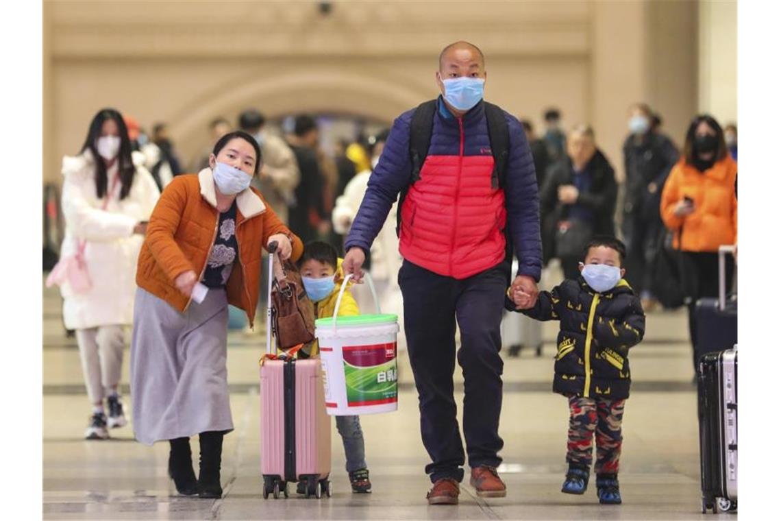 Reisende mit Atemschutzmasken gehen durch den Bahnhof Hankou in der chinesischen Stadt Wuhan. Foto: Uncredited/CHINATOPIX/AP/dpa