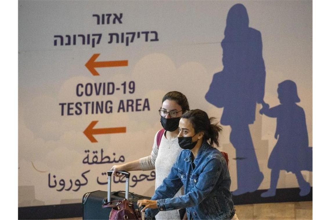 Reisende mit Mund-Nasen-Schutz kommen am Ben-Gurion-Flughafen an. Israel hat die Handy-Überwachung von Omikron-Infizierten beendet. Foto: Ariel Schalit/AP/dpa