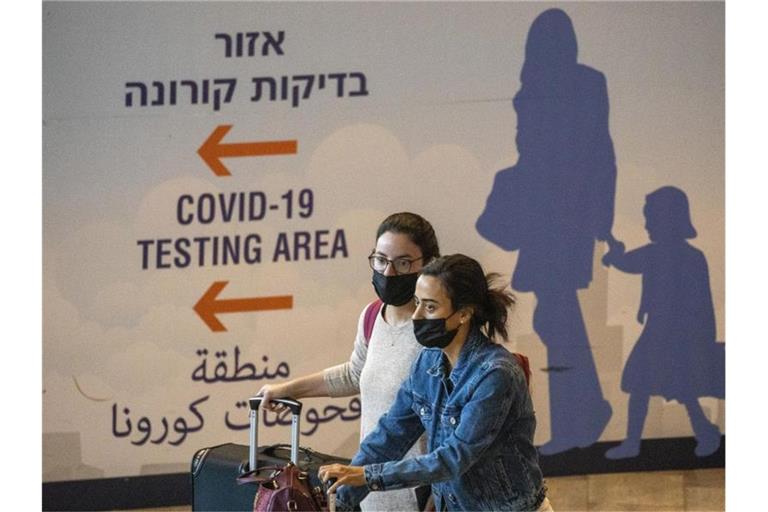 Reisende mit Mund-Nasen-Schutz kommen am Ben-Gurion-Flughafen an. Israel hat die Handy-Überwachung von Omikron-Infizierten beendet. Foto: Ariel Schalit/AP/dpa