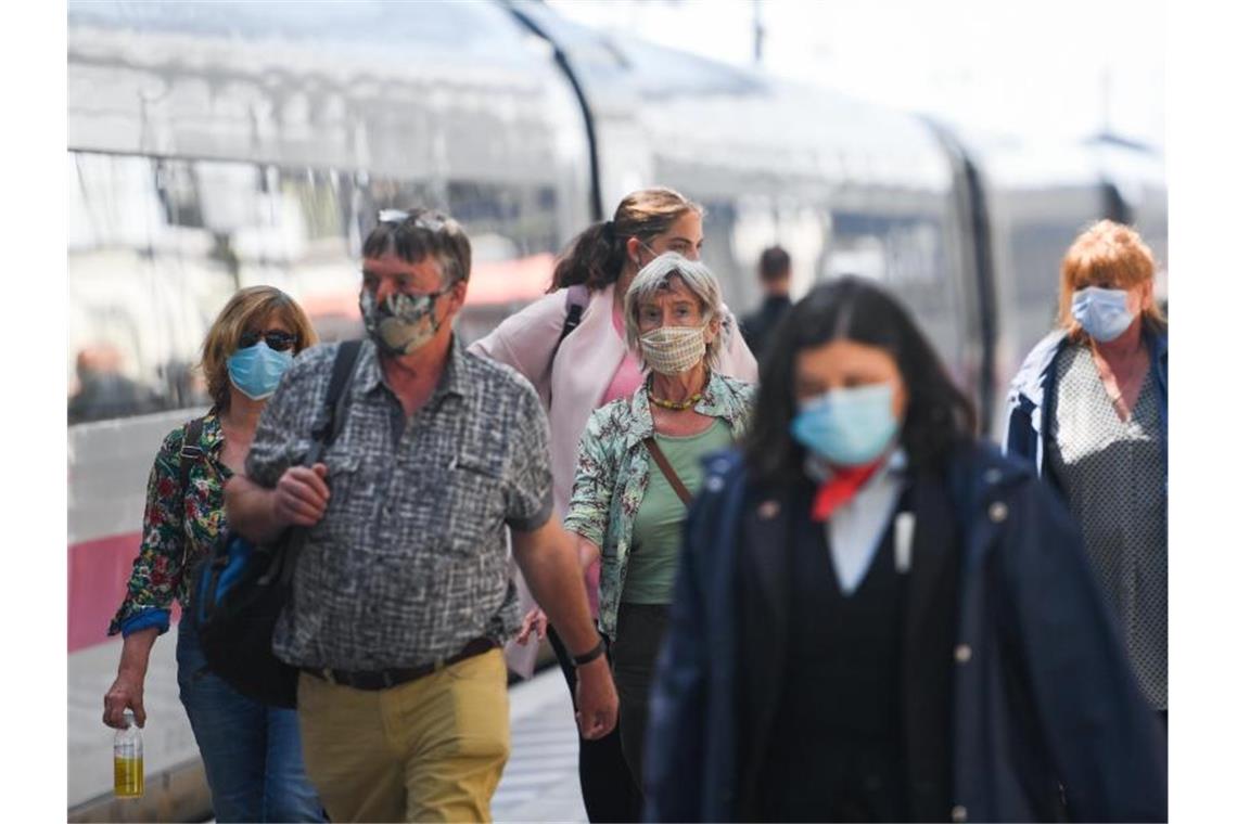 Auch bei guter Corona-Tendenz weiter Infektionsgefahr Reisende sind mit Mundschutz auf dem Frankfurter Hauptbahnhof unterwegs. Foto: Arne Dedert/dpa