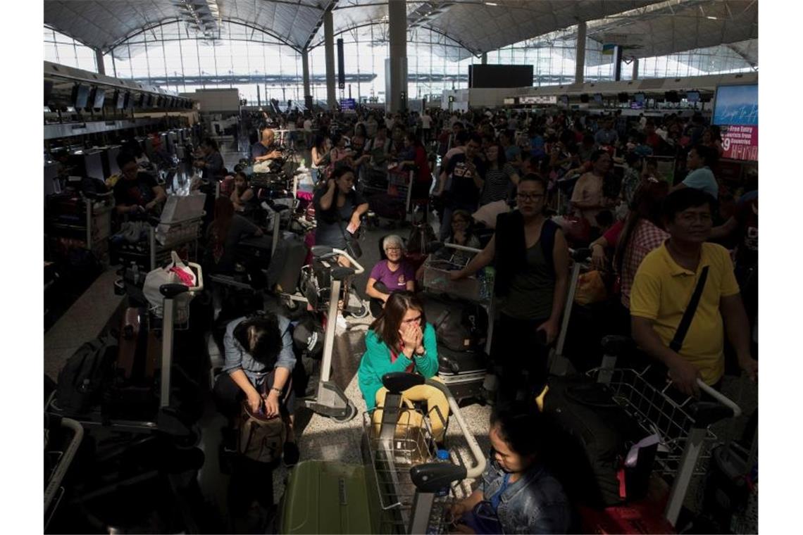 Heftige Zusammenstöße in Hongkongs Flughafen Reisende warten am Terminal des Flughafens. Hongkongs Protestbewegung hat den Flughafen der Stadt den zweiten Tag in Folge zum Stillstand gebracht. Foto: Vincent Thian/AP