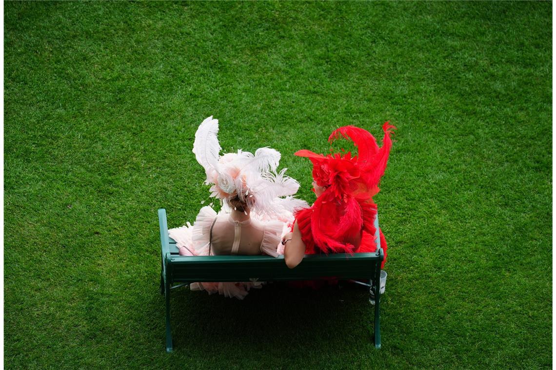 Rennbesucherinnen sitzen auf einer Bank am ersten Tag des Royal Ascot auf der Pferderennbahn von Ascot.