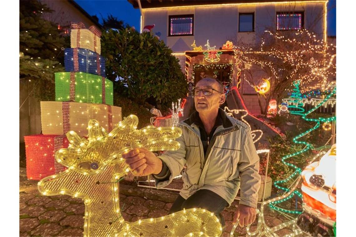 Rentner Josef Johann baut vor seinem Haus im Moseldorf Klotten bunte leuchtende Weihnachtsdekoration auf. Foto: Thomas Frey/dpa