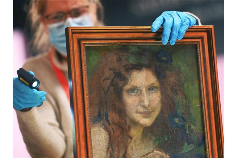 Restauratorin Andrea Wähning überprüft mit einer Speziallampe das Gemälde „Das Mädchen mit blaugrünen Augen“ von Julie Wolfthorn. Foto: Uli Deck/dpa