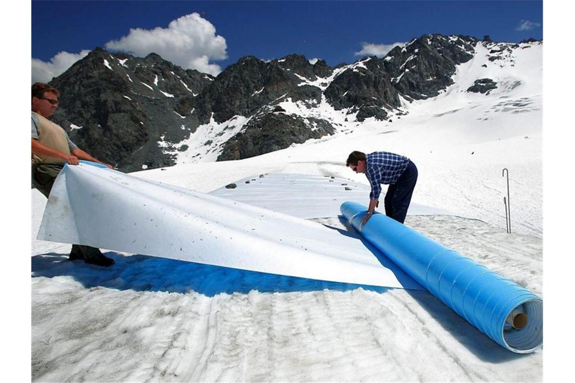 Retten, was zu retten ist: Helfer rollen im Hochsommer schützende Planen auf dem Tortin-Gletscher in der Schweiz aus. Foto: epa Keystone Olivier Maire/epa Keystone/dpa