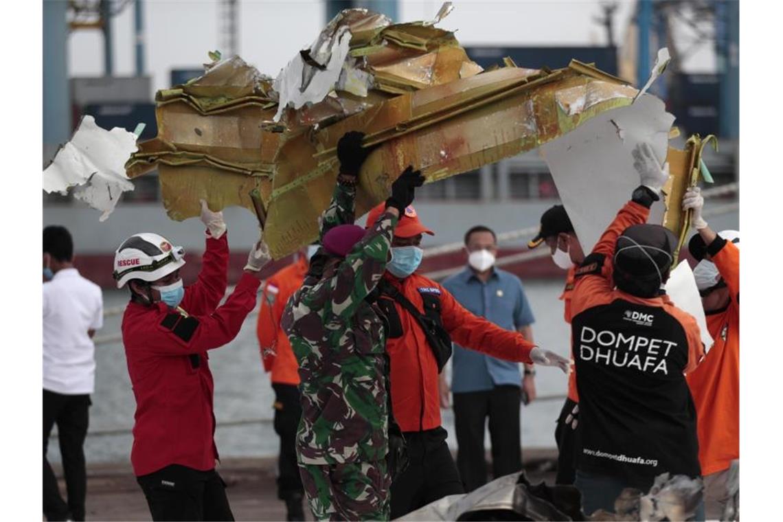 Schwierige Bergungsarbeiten nach Flugzeugabsturz vor Java Rettungshelfer tragen ein Teil des Flugzeugs, das aus der Javasee geborgen wurde. Foto: Dita Alangkara/AP/dpa
