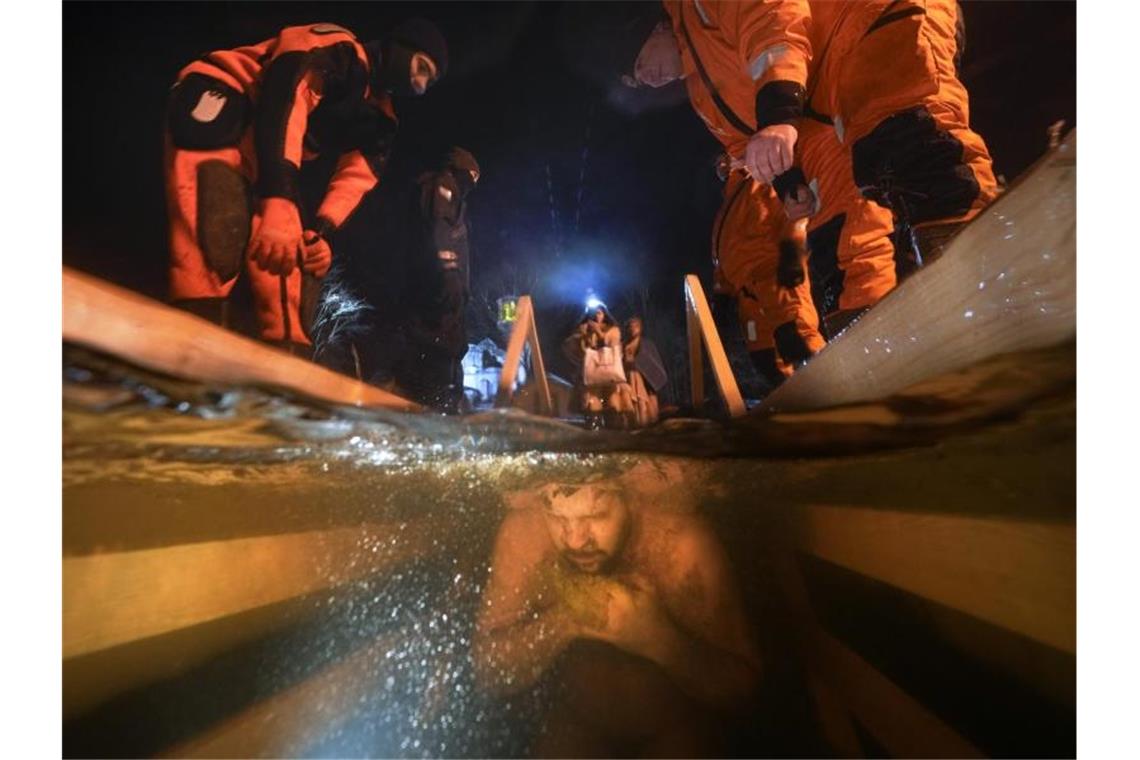 Rettungskräfte beobachten einen russisch-orthodoxen Gläubigen, der während des Dreikönigsfestes in das eiskalte Wasser eintaucht. Foto: Dmitri Lovetsky/AP/dpa