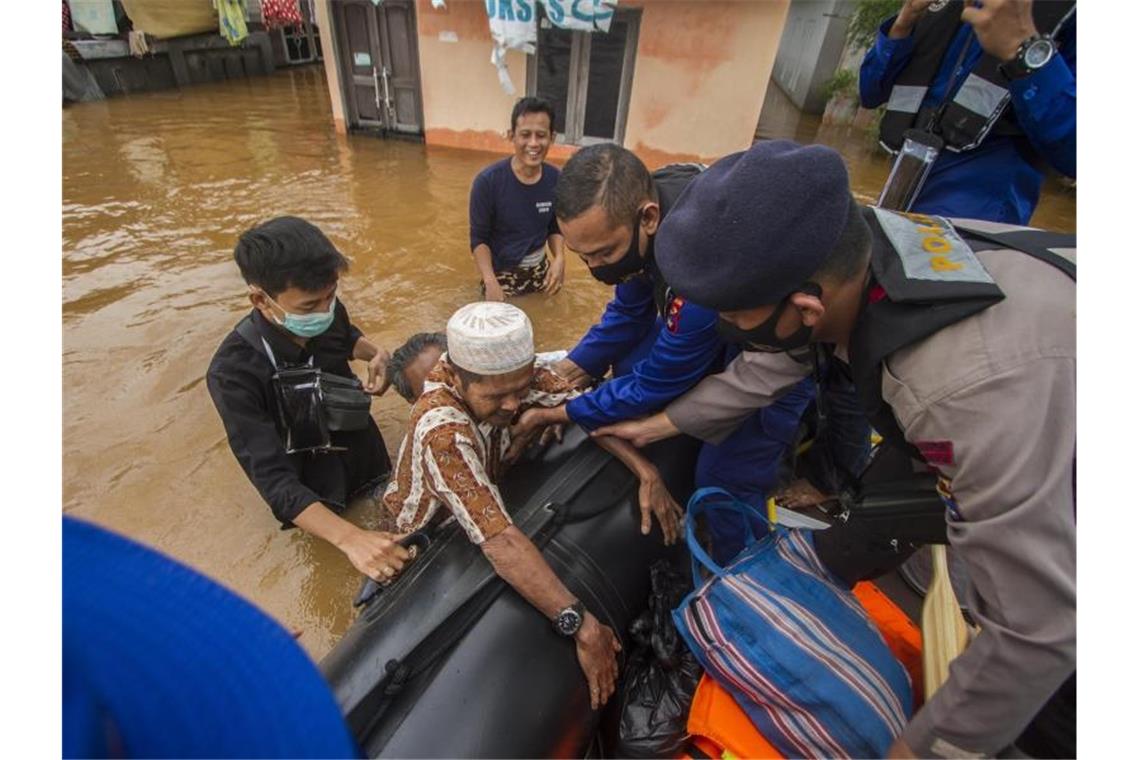 Rettungskräfte helfen einem älteren Mann in einem überfluteten Dorf in ihr Boot. Foto: Putra/AP/dpa