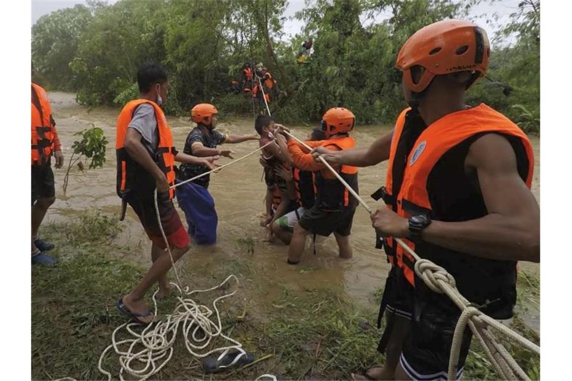Tropensturm auf Philippinen fordert mindestens 30 Tote Rettungskräfte in Cagayan helfen während einer Evakuierung einem Kind. Foto: PHILIPPINE COAST GUARD/AP/dpa