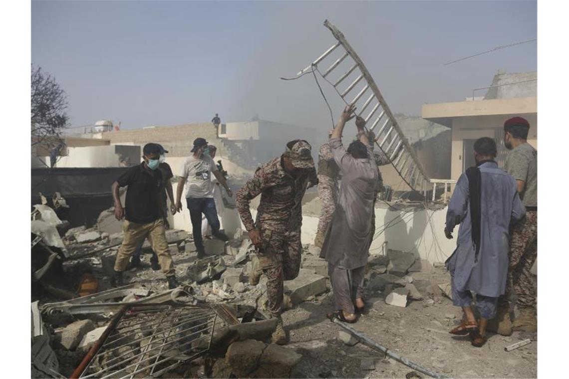 Viele Tote bei Absturz von Passagierflugzeug in Pakistan Rettungskräfte und Anwohner an der Absturzstelle. Foto: Fareed Khan/AP/dpa