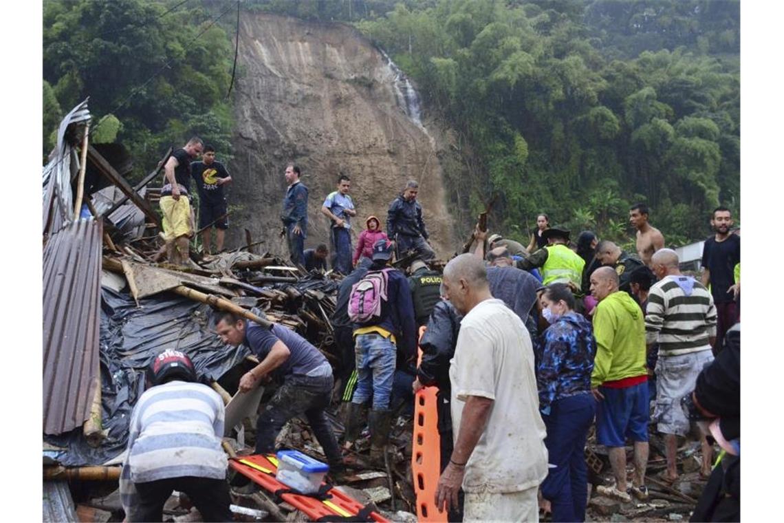 Rettungskräfte und Einwohner suchen zwischen den Trümmern der weggerissenen Häuser nach Überlebenden. Foto: Andres Otalvaro/AP/dpa