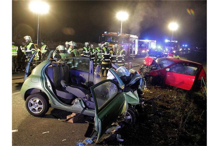 Rettungskräfte und zwei zerstörte Fahrzeuge stehen an einer Unfallstelle. Foto: Josef Reisner/dpa