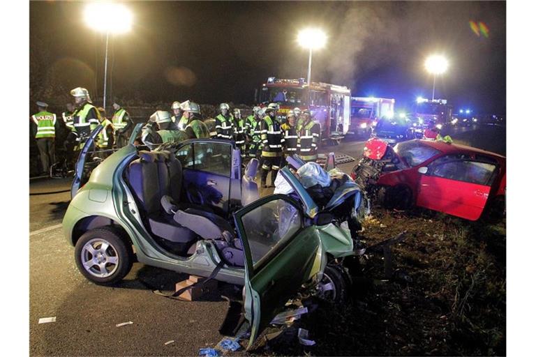 Rettungskräfte und zwei zerstörte Fahrzeuge stehen an einer Unfallstelle. Foto: Josef Reisner/dpa/Archivbild