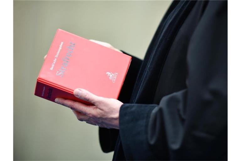 Richter in einem Verhandlungssaal des Landgerichts mit einem Buch mit der Aufschrift „Strafrecht“. Foto: Uwe Anspach/dpa