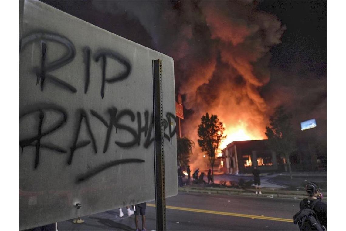 „RIP Rayshard“ steht auf einem Schild, während im Hintergrund ein Wendy's-Restaurant brennt. Foto: Ben Gray/Atlanta Journal-Constitution/AP/dpa