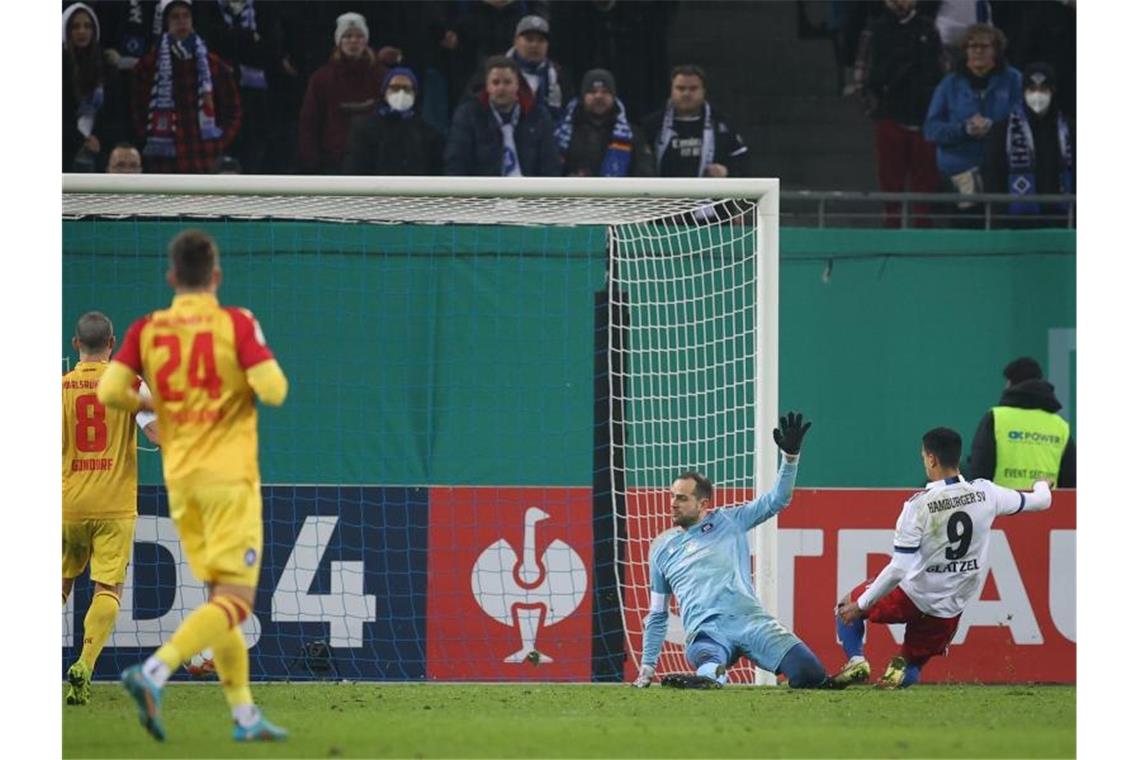HSV siegt im Elfmeterschießen gegen zehn Karlsruher Robert Glatzel (r) vom HSV trifft zum 2:2 gegen Karlsruhes Torwart Marius Gersbeck. Foto: Christian Charisius/dpa