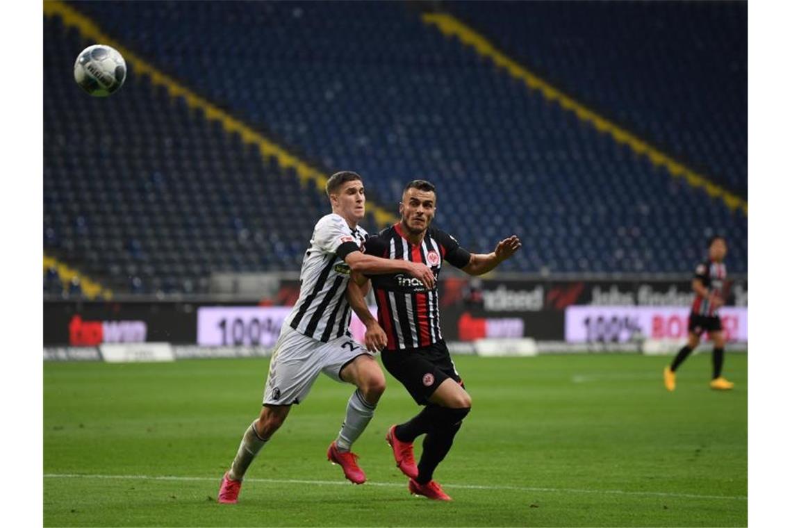 Robin Koch aus Freiburg und Filip Kostic aus Frankfurt (l-r.) im Zweikampf um den Ball. Foto: Arne Dedert/dpa-Pool/dpa