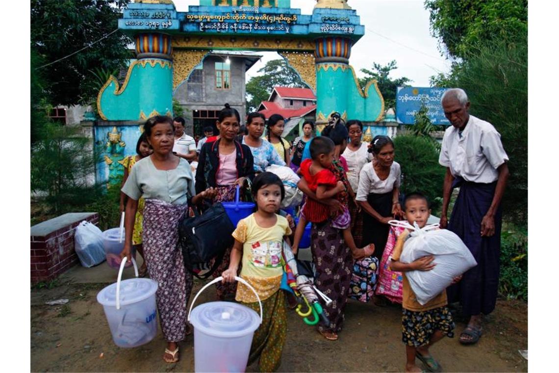 Rohingya, die aus dem Kampfgebiet geflohen sind, tragen ihr Hab und Gut bei der Ankunft in einem Kloster. Foto: Nyunt Win/epa/dpa