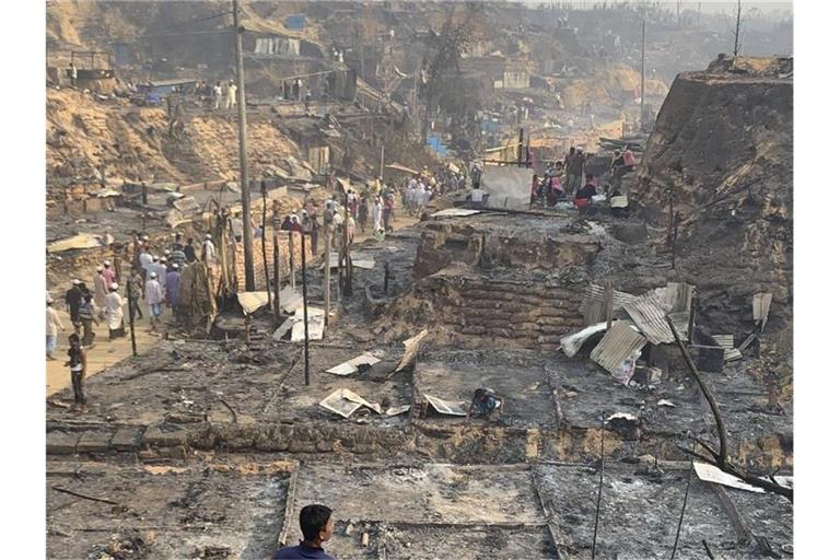 Rohingya-Geflüchtete betrachten nach dem Brand die Überreste des Flüchtlingslager. Foto: Shafiqur Rahman/AP/dpa