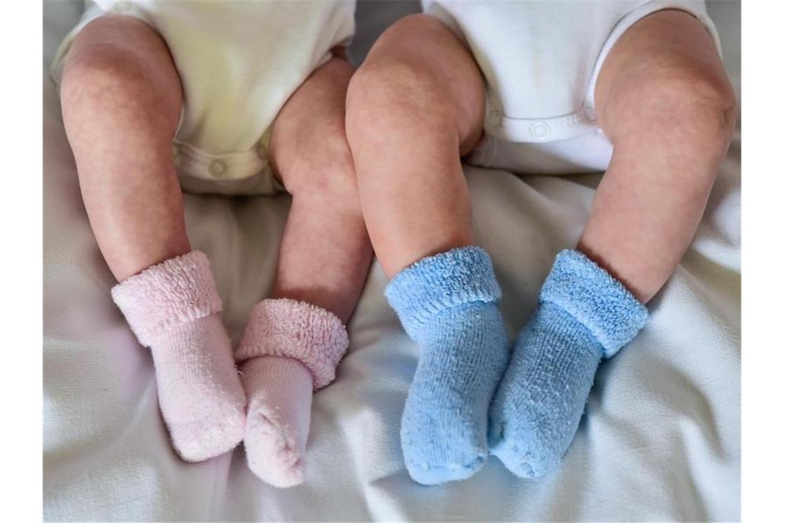 Rosa und blaue Söckchen für ein Mädchen und einen Jungen und die nackten Babybeine von Zwillingen. Foto: Patrick Pleul/dpa-Zentralbild/dpa/Archiv