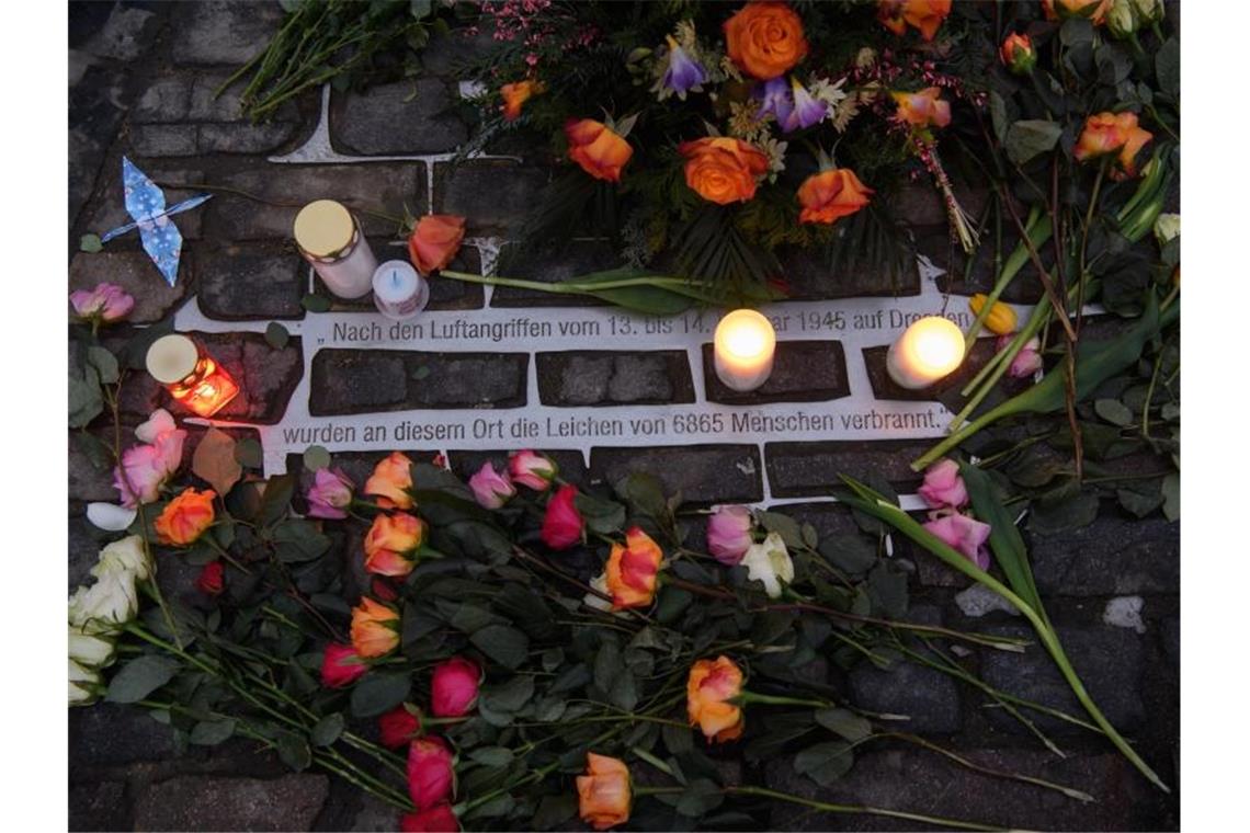 Rosen liegen am 76. Jahrestag der Zerstörung Dresdens im Zweiten Weltkrieg auf dem Altmarkt an einer Gedenkstätte. Foto: Robert Michael/dpa-Zentralbild/dpa