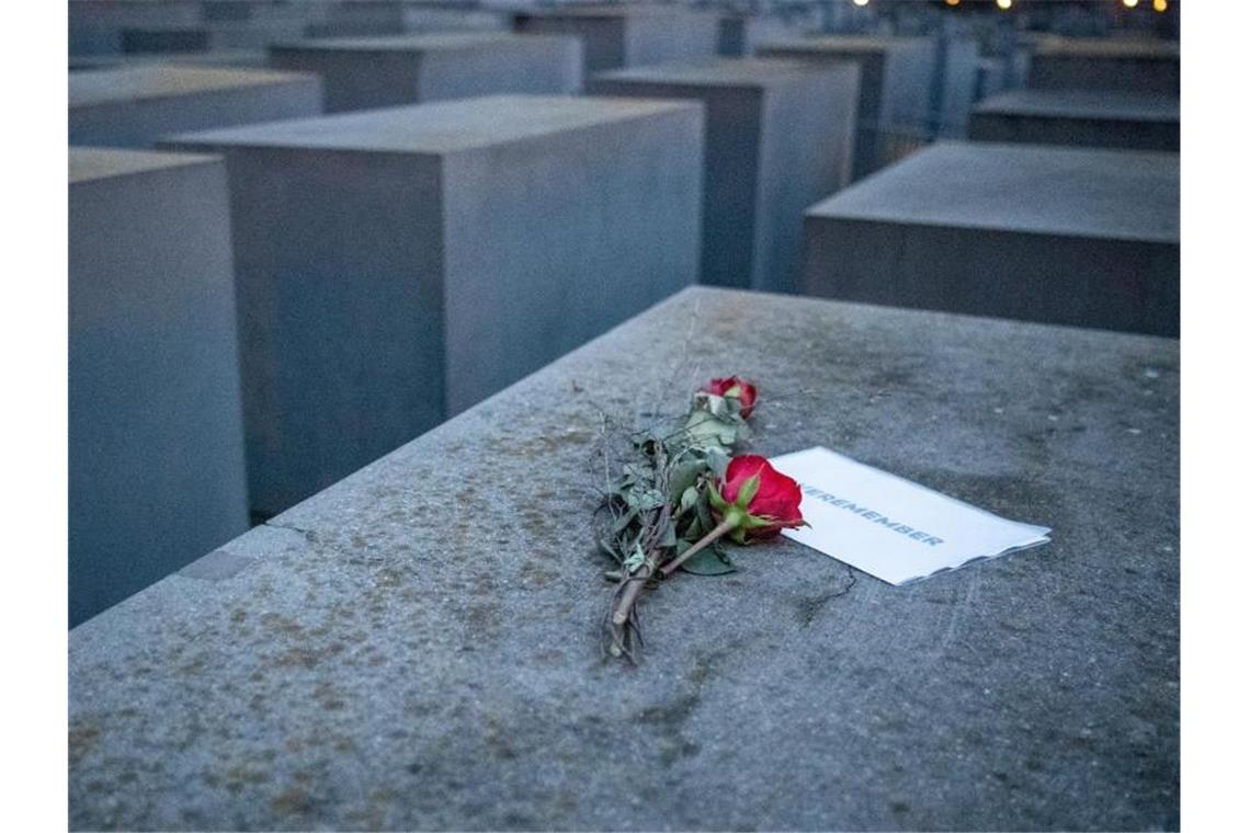 Rosen liegen mit einem Zettel mit der Aufschrift „#weremember“ am Holocaust-Mahnmal in Berlin. Foto: Dorothee Barth/dpa