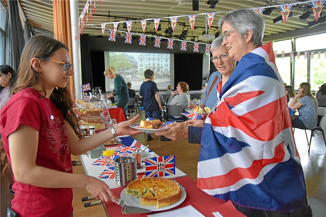 Rosina Knecht (rechts), Englischlehrerin aus Heilbronn, holt sich ein Stück Coronation Quiche. Zur Feier des Tages hat sie sich eine britische Flagge um die Schultern gelegt.