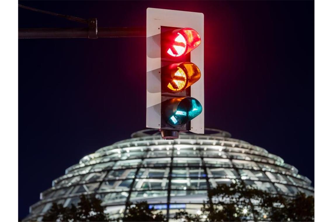 Rot-gelb-grün - eine Ampel leuchtet vor der Kuppel des Reichstagsgebäudes (in einer Langzeitbelichtung) in allen drei Phasen. Foto: Christoph Soeder/dpa