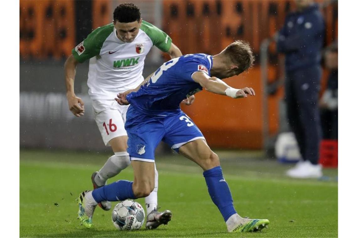 Ruben Vargas (l) von Augsburg und Stefan Posch von Hoffenheim in Aktion. Foto: Michael Probst/AP/POOL/dpa