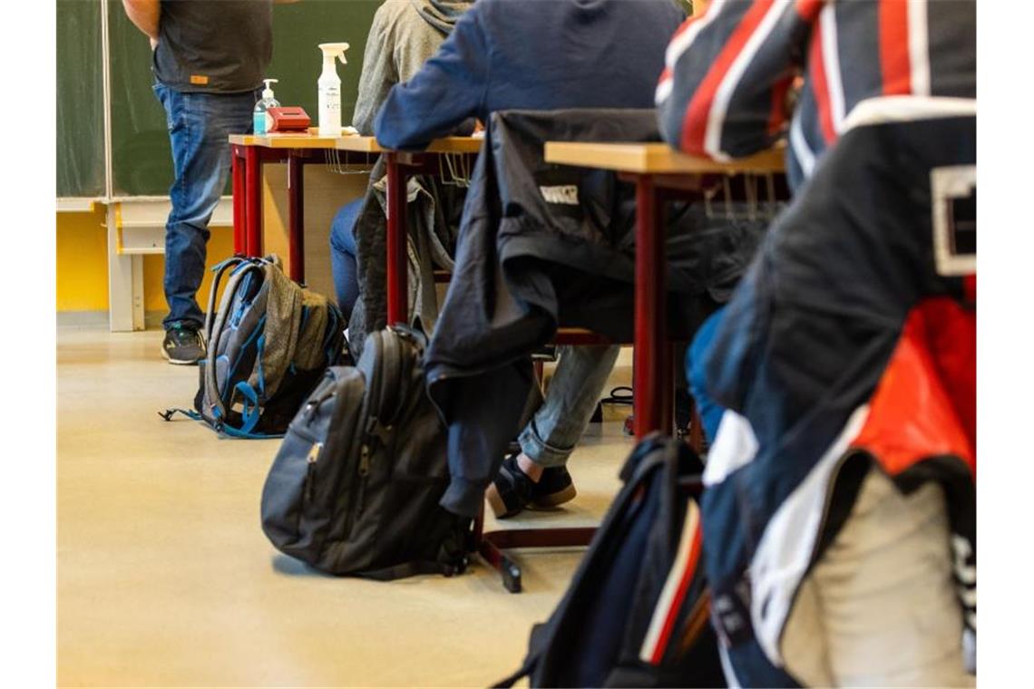 Rucksäcke stehen neben den Tischen, an denen die Schülerinnen und Schüler beim Unterricht in ihrer Klasse sitzen. Foto: Philipp von Ditfurth/dpa