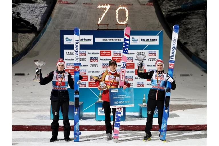 Ryoyu Kobayashi (M) jubelt mit dem Pokal für den Gesamtsieger, einem goldenen Adler, neben dem Gesamtzweiten Marius Lindvik (l) und dem Gesamtdritten Halvor Egner Granerud. Foto: Daniel Karmann/dpa