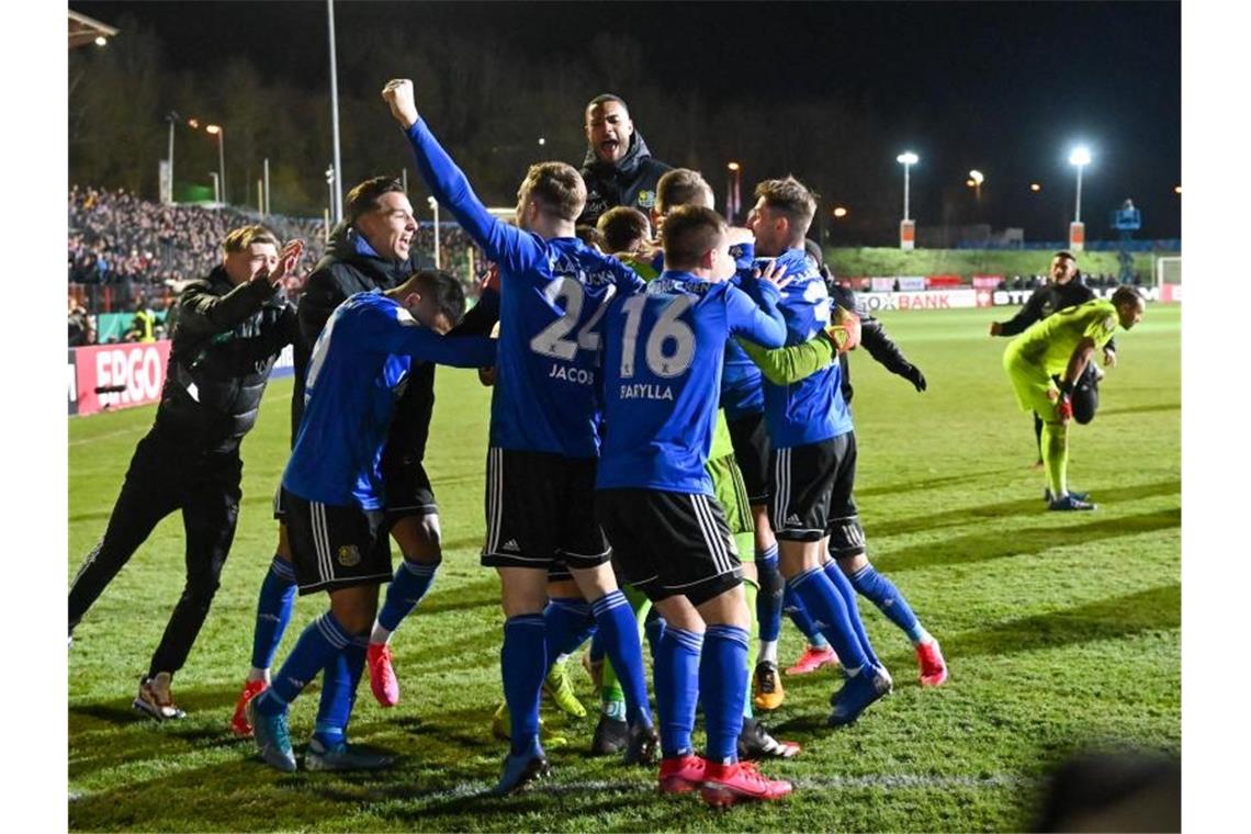 Wo das Coronavirus Sportler und Teams ausbremste Saarbrückens Spieler feiern das gewonnene Elfmeterschießen und den Einzug ins Halbfinale des DFB-Pokals - dann kam das Coronavirus. Foto: Oliver Dietze/dpa