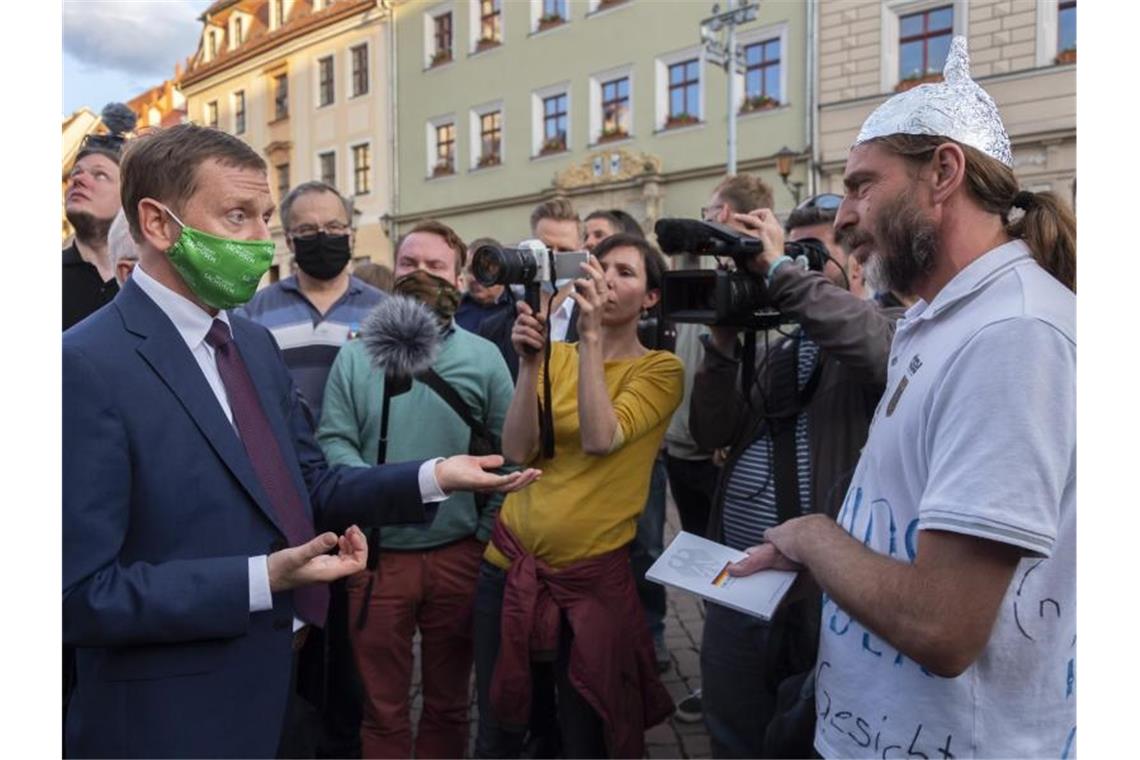 Sachsens Ministerpräsident Michael Kretschmer (l) spricht in Pirna mit einem Gegner der Corona-Maßnahmen. Foto: Matthias Rietschel/dpa-Zentralbild/dpa
