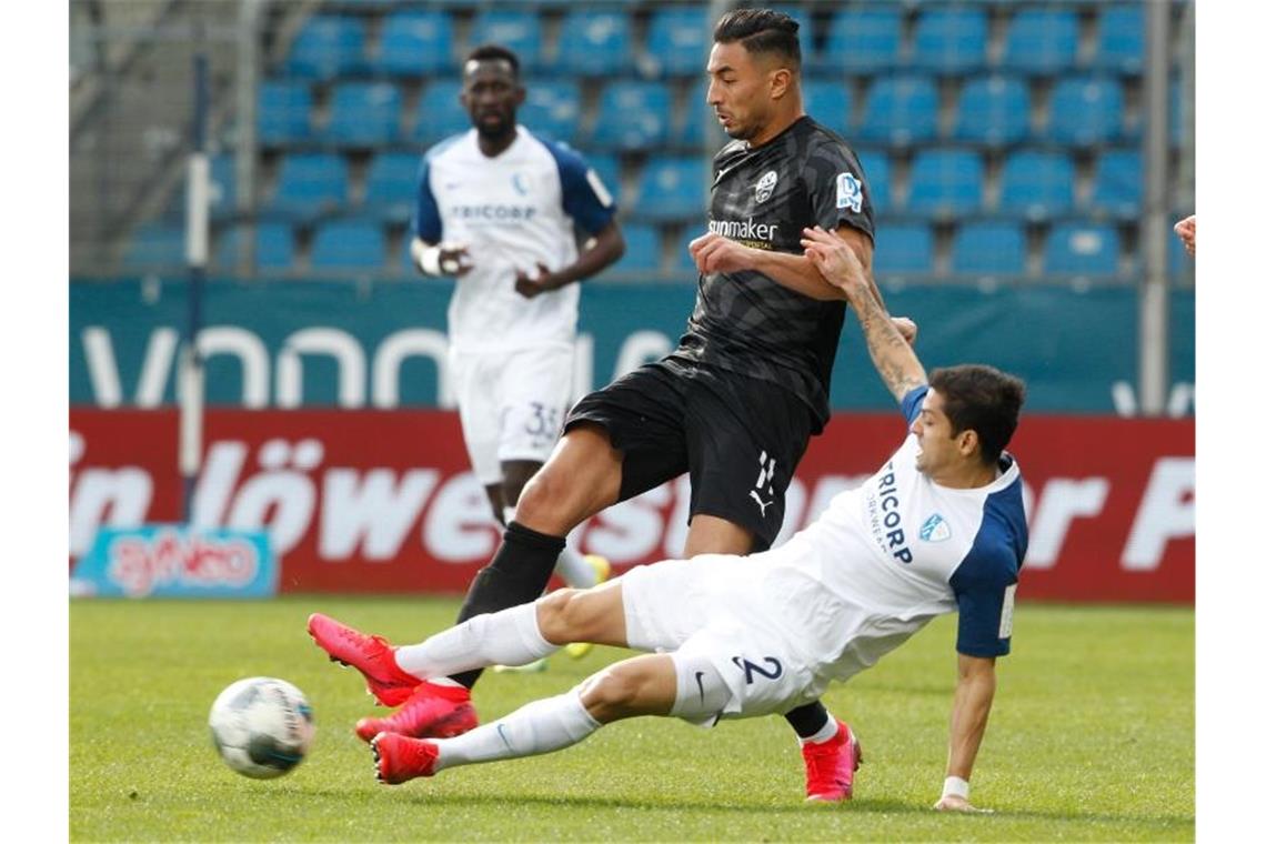 Sandhausens Aziz Bouhaddouz (l.) und Bochums Cristian Gamboa kämpfen um den Ball. Foto: Roland Weihrauch/dpa