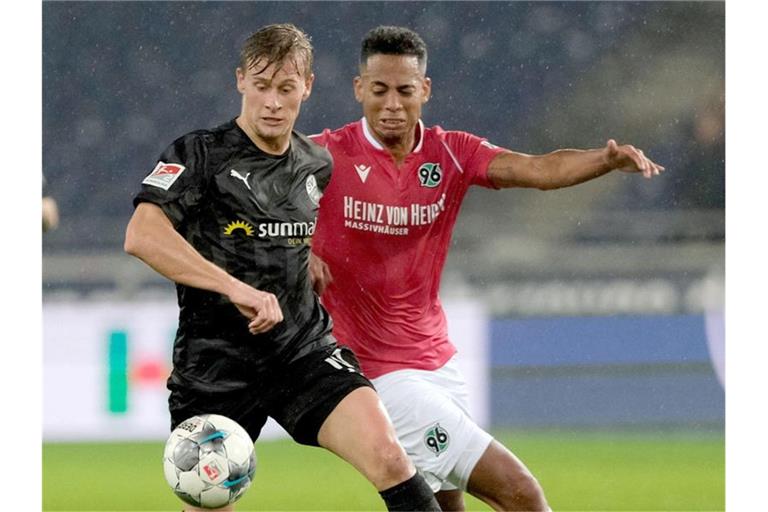 Sandhausens Julius Biada (l.) und Hannovers Dennis Aogo kämpfen um den Ball. Foto: Peter Steffen/dpa