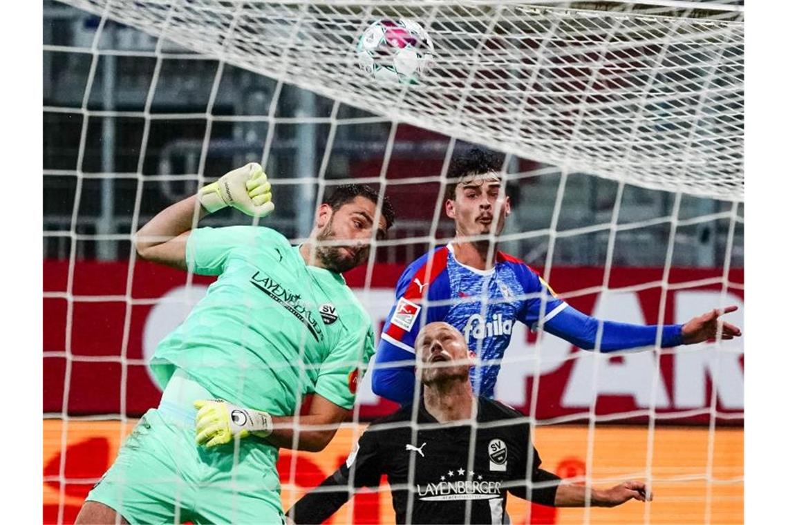 Sieg über Sandhausen: Holstein Kiel rückt auf Platz drei vor Sandhausens Torwart Stefanos Kapino (l-r), Sandhausens Gerrit Nauber und Kiels Janni Serra kämpfen um den Ball. Foto: Axel Heimken/dpa