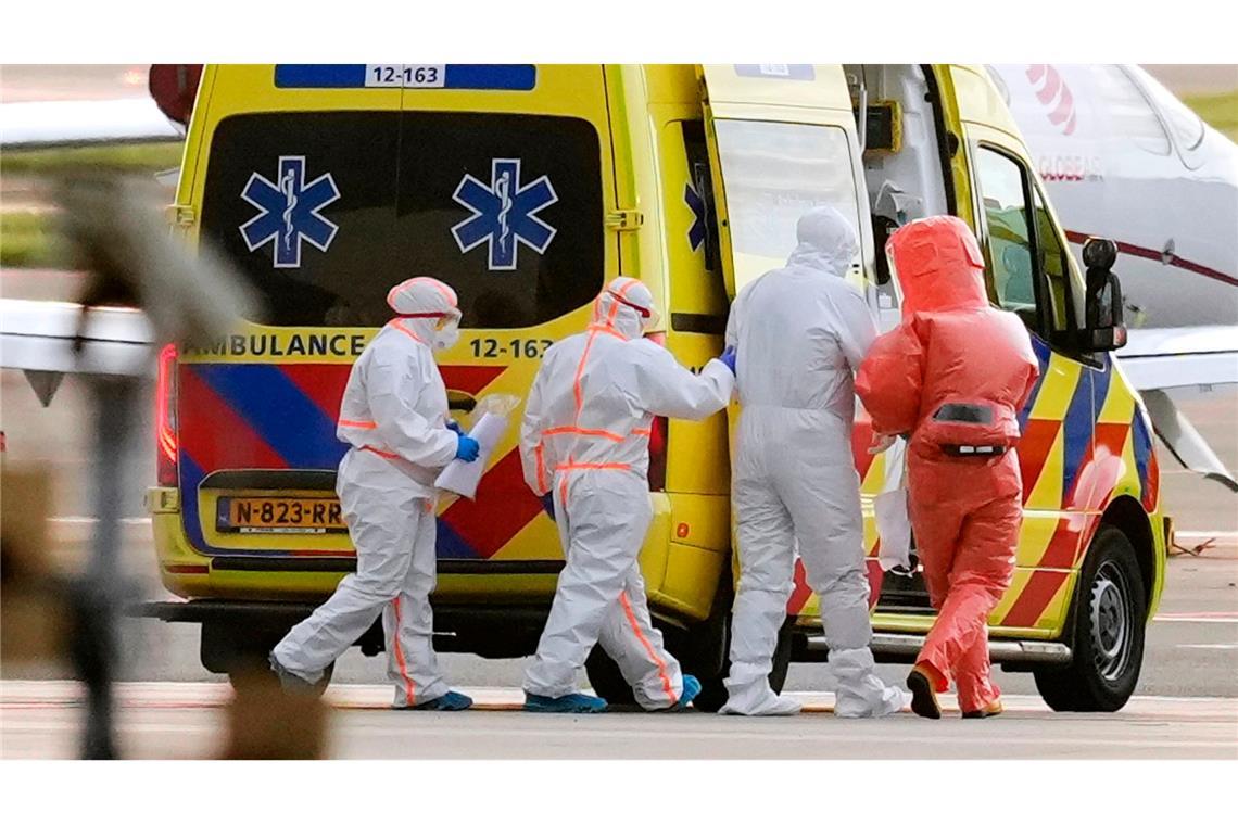 Sanitäter begleiteten eine Person mit Verdacht auf eine Hantavirus-Infektion auf dem Amsterdamer Flughafen zu einem Krankenwagen.